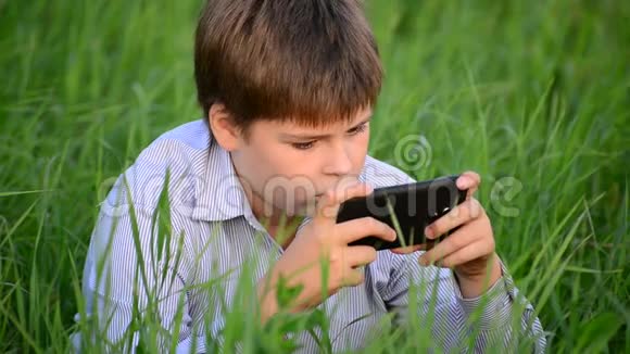 少年在草地上使用智能手机视频的预览图