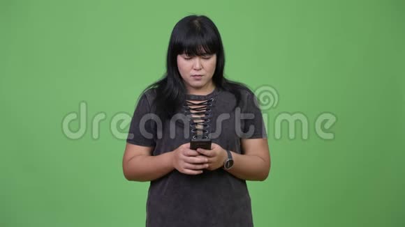 快乐超重的亚洲女人思考电话视频的预览图