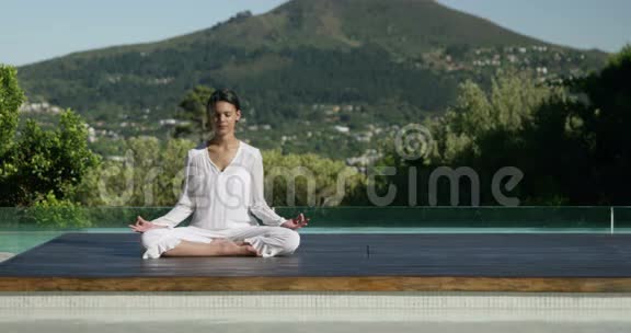 平静的女人在泳池边做瑜伽视频的预览图