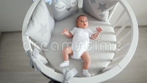 新生儿躺在白色的圆床上有移动设备视频的预览图