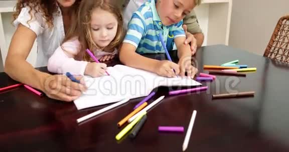 可爱的孩子和他们的父母一起在桌子旁画画视频的预览图