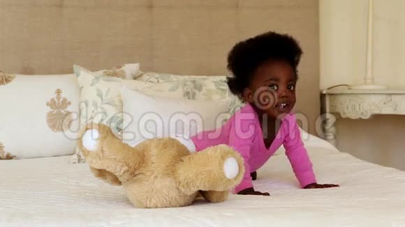 可爱的女婴在床上玩玩具熊视频的预览图