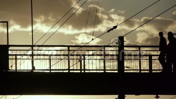 旧钢桥上穿越铁路的人群剪影视频的预览图