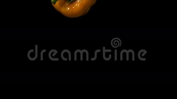 黄色的胡椒落在黑色背景的水里视频的预览图