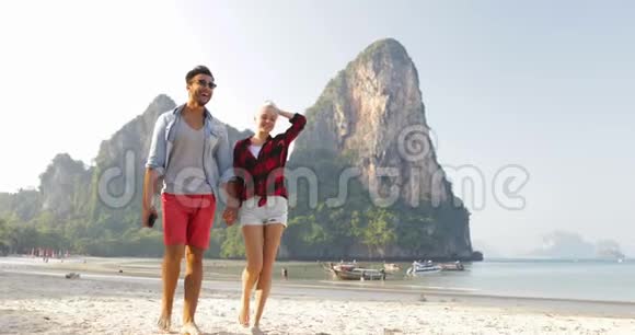 情侣在沙滩上散步手牵手聊天青年男女游客度假视频的预览图