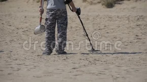 带金属探测器的人沿着海滨的沙滩漫步慢动作视频的预览图