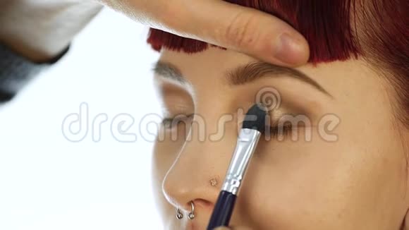 专业化妆师日常化妆的特写用刷子把粉涂在女人的脸颊上视频的预览图
