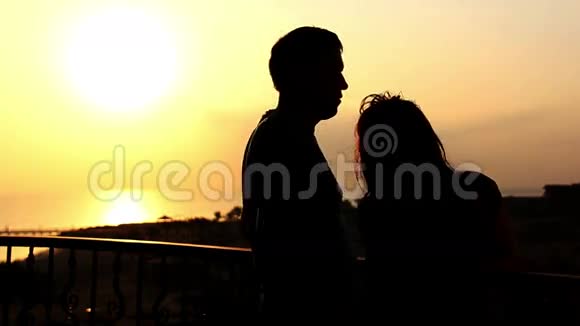 日落阳台上一对爱的情侣在海边拥抱和亲吻的剪影视频的预览图