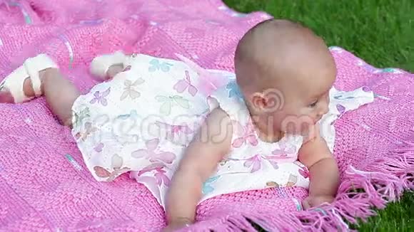 公园里的粉色毯子上快乐的微笑快乐的女婴视频的预览图