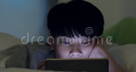 可爱的亚洲男孩在平板电脑上默默地看着和玩视频的预览图