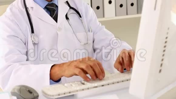 专注的医生用他的电脑坐在办公桌前视频的预览图