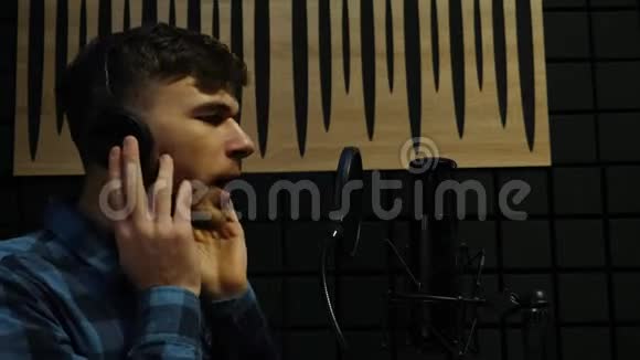 录音室的男歌手戴着耳机职业音乐家在家庭音乐工作室有感情地演唱和录制歌曲视频的预览图