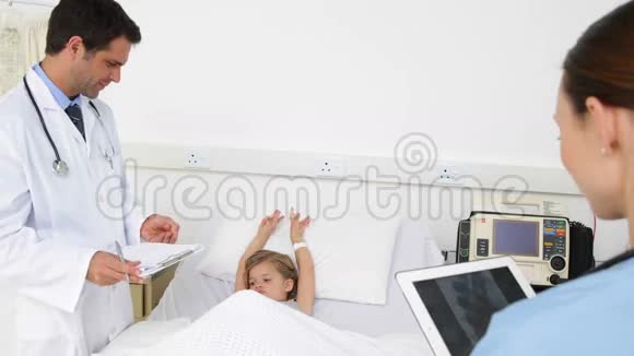 生病的小女孩躺在床上与护士和医生交谈视频的预览图