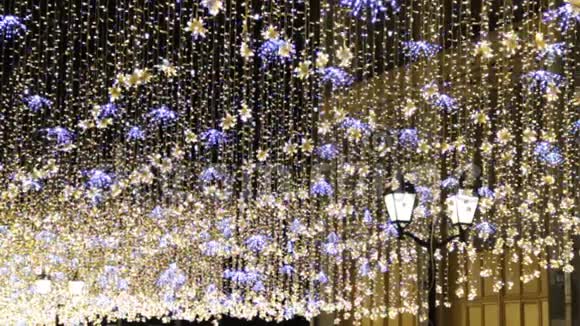 圣诞节和新年假期晚上在城市街道的户外照明金光闪闪挥舞着花环视频的预览图