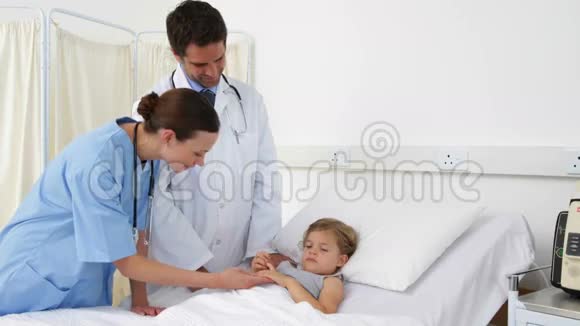 生病的小女孩躺在床上与护士和医生交谈视频的预览图