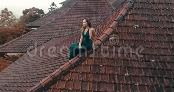 坐在红房子屋顶上的漂亮女人视频的预览图
