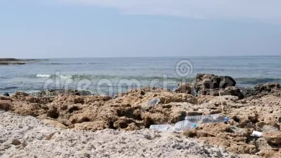 塑料瓶躺在岩石污染的海滩上环境问题概念慢动作视频的预览图