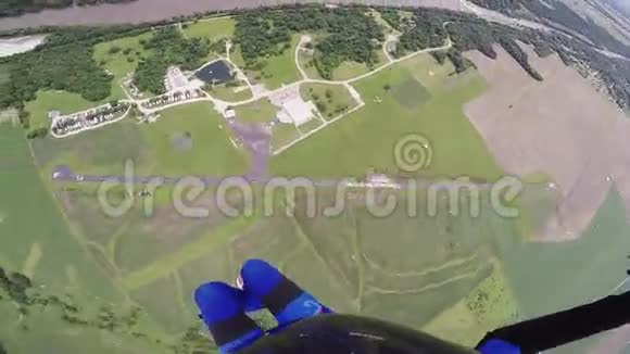 专业跳伞员跳伞在绿色平原河流上空景观视频的预览图