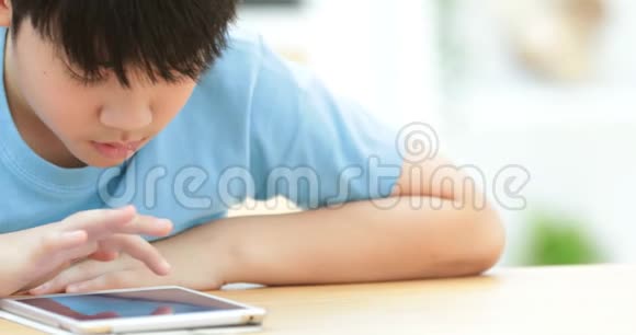 可爱的亚洲男孩在平板电脑上默默地看着和玩视频的预览图