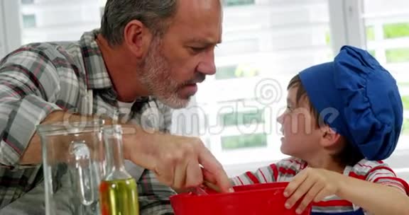 爸爸和男孩在碗里搅拌面团视频的预览图