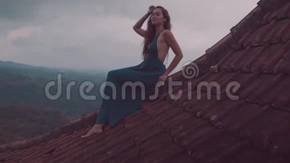 坐在红房子屋顶上的漂亮女人视频的预览图