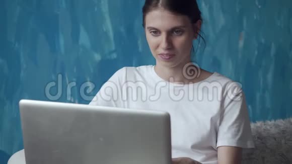 女人在房间里坐在沙发上用笔记本电脑工作视频的预览图