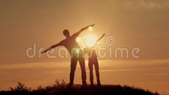 父亲和儿子的剪影在日落海滩上嬉戏视频的预览图