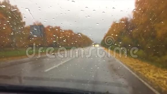 汽车在柏油路上行驶秋游山林美景雨滴落在玻璃车上模糊背景行车视频的预览图