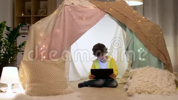 带平板电脑的小男孩在家里的儿童帐篷里视频的预览图