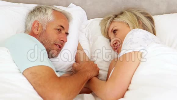 快乐的一对夫妻在床上聊天牵手视频的预览图