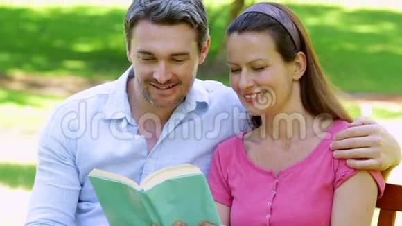 一对坐在公园长椅上一起读书的夫妇视频的预览图