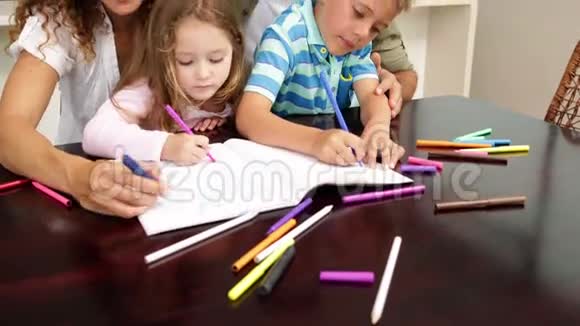 可爱的孩子和他们的父母一起在桌子旁画画视频的预览图