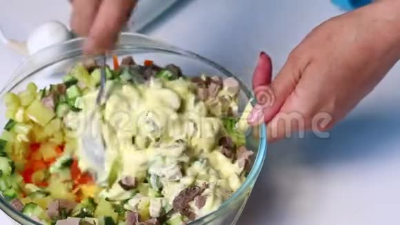 俄罗斯肉类沙拉配蔬菜和蛋黄酱一位妇女正在把蛋黄酱和色拉的配料混合在一起视频的预览图