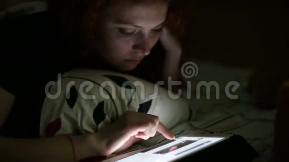 晚上躺在家里的一个年轻女人在床上视频的预览图