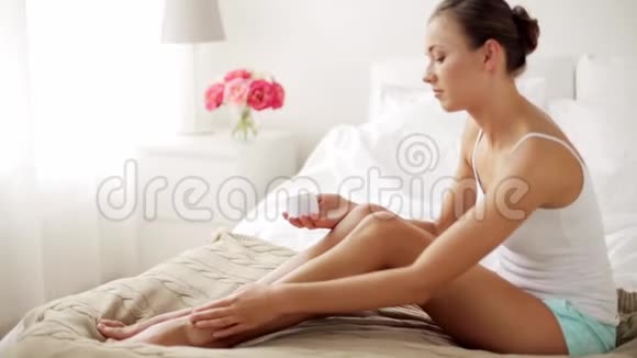 漂亮的女人在家里给她的腿抹奶油视频的预览图