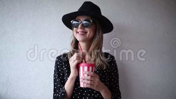 戴着帽子和太阳镜的女人喝了一杯视频的预览图