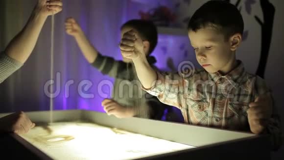 孩子们用双手在沙子上用光照画画视频的预览图
