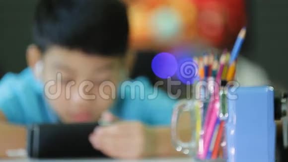 穿着校服的亚洲男孩正在家里用白纸作画视频的预览图