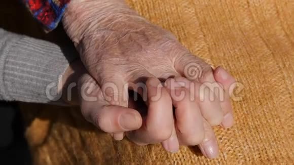 一只年轻的雌性手安慰着一双老奶奶的双手在户外亲密起来视频的预览图