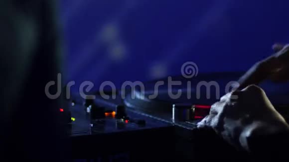 一个DJ在俱乐部的音响调音台上混合音乐视频的预览图