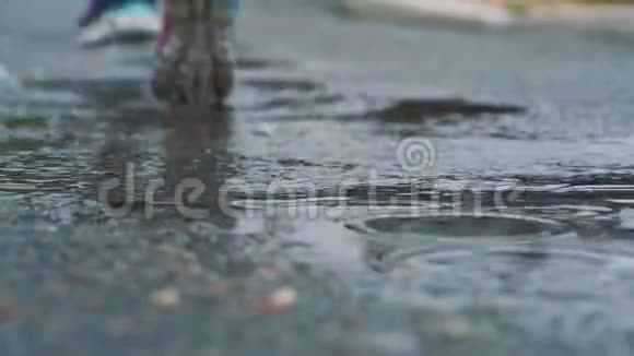 穿运动鞋的跑步者的腿的特写镜头女运动员在公园里慢跑踩在泥泞的水坑里视频的预览图