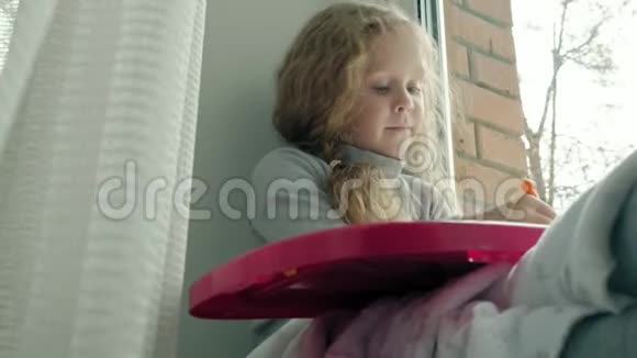 一个红色波浪发的小女孩坐在窗台上画在一块磁性的木板上教育的概念视频的预览图