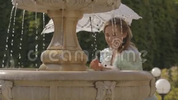 在喷泉前拿着白色雨伞的女孩视频的预览图