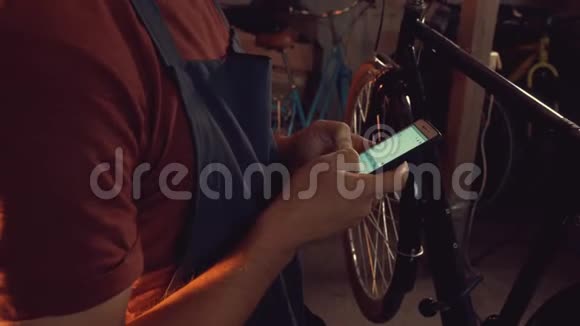 主题小企业自行车修复年轻的白种人黑发男子戴着安全护目镜手套使用移动电话视频的预览图