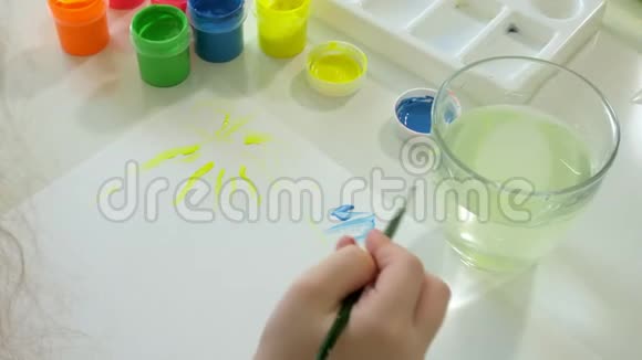 小红发姑娘坐在桌旁用颜料和画笔作画视频的预览图