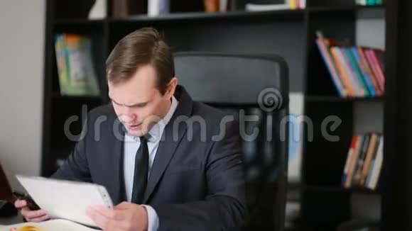 有魅力的商人在办公室里用电脑和文件工作视频的预览图