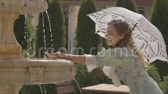 在喷泉前拿着白色雨伞的女孩视频的预览图