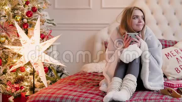 圣诞节室内的年轻女子坐着一个格子和一杯茶视频的预览图