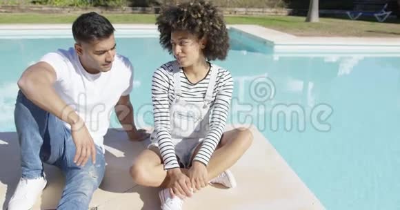 年轻夫妇在游泳池的阳光下放松视频的预览图