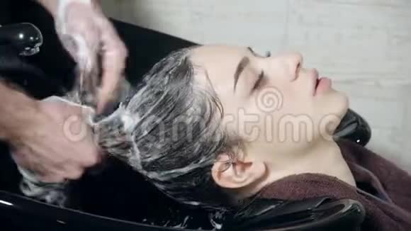 美丽的女孩在美容院理发前洗头在美发店洗头年轻的白种人女孩视频的预览图